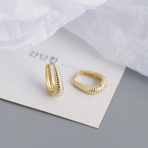 Macro shot of gold-plated twisted hoop earrings with a textured croissant pattern