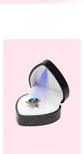 Macro view of heart-shaped jewelry box with LED spotlight illuminating a blue gemstone ring