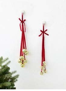 Close-up of golden metal bells with star cutouts and red velvet ribbons for Christmas