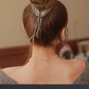Silver wing hair clip with rhinestones and long tassels on an elegant bun hairstyle