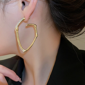 Detail of large gold heart hoop earrings with bamboo texture and rhinestone studs