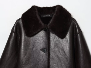 Détail de la veste en similicuir marron foncé avec col en peluche et boutons élégants