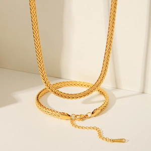 Macro detail of 18K gold braided chain with S.STEEL engraved tag and lobster clasp