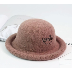 Detail of a pink wool felt hat featuring a black embroidered smile and rolled brim edge
