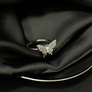 Detail view of silver butterfly ring with small diamonds and pearl on black silk