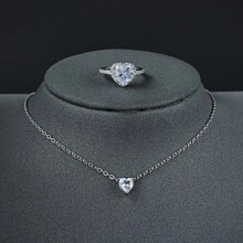 Detail view of silver heart-shaped gemstone necklace and ring set on velvet display