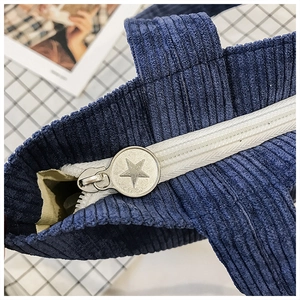 Detail view of blue corduroy handbag with star-shaped zipper puller and striped texture