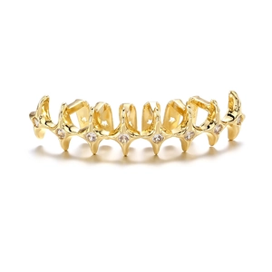 Macro shot of gold hip-hop grillz with eight star-shaped parts set with cubic zirconia stones