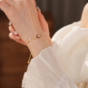 Luxury gold plated heart charm bracelet with pearls and red enamel on female wrist