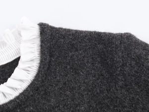 Close-up of charcoal grey knit jacket featuring white poplin ruffled collar detail