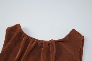 Detail of a brown sleeveless dress showing the pleated crew neck and ribbed knit fabric
