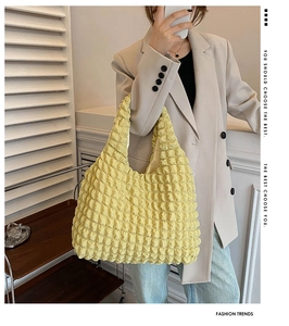 Detail of yellow pleated cloud shoulder bag showing bubble texture on a fashion model
