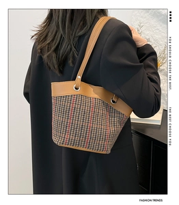 Detail of checkered canvas bucket bag with leather trim and metal eyelet accents