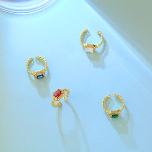 Detailweergave van vier vergulde open ringen met kleurrijke rechthoekige zirkoonstenen