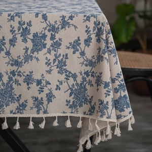 Close-up of blue floral porcelain pattern and beige tassel fringe on linen tablecloth