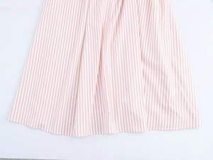 Detail of pink striped dress fabric showing pleated hem and soft flowing texture