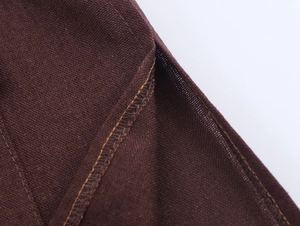 Detailed close-up of brown cotton linen fabric texture with yellow contrast stitching