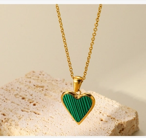 Macro detail of heart-shaped gold necklace with striped green malachite inlay