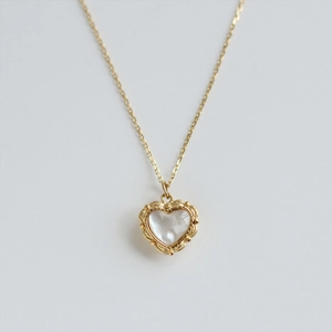 Golden heart necklace with white pearl shell pendant on a minimalist white background