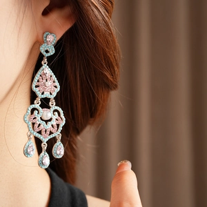 Détail d'une boucle d'oreille vintage à pompons avec strass roses et perles sur mannequin