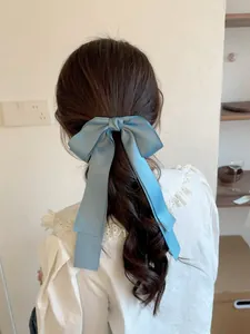 Gros plan d'une grande pince à cheveux nœud en satin bleu poudré sur cheveux bruns