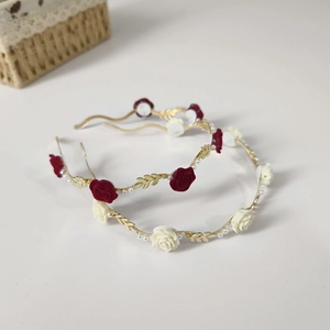 Detail of elegant gold wavy headbands with velvet roses and white pearls on white background