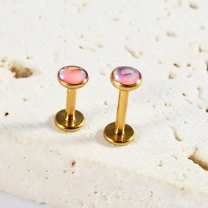Macro shot of gold stainless steel labret studs with iridescent pink opal stones