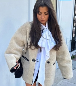 Détail de la veste en peau de mouton beige avec boutons noirs et texture peluche