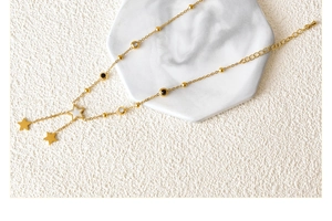 Detail shot of a star and moon tassel anklet on a white marble coaster background