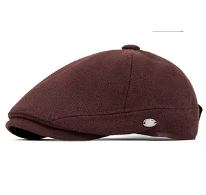Detail of burgundy wool beret featuring side metal logo and textured vintage fabric