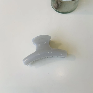 Detail view of a minimalist dusty purple hair claw clip on a clean white surface