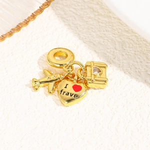 Detailed view of gold travel pendants featuring a plane, heart, and luggage charm