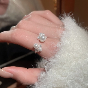 Elegant pearl and zircon open ring shown worn on finger against soft white sweater