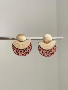 Close-up of geometric earrings with golden brushed metal finish and leopard print details