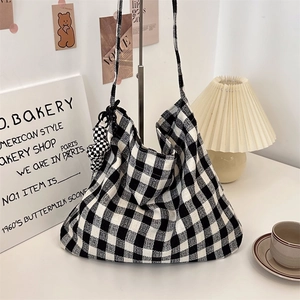 Close-up of black and white checkered canvas tote bag with a heart-shaped charm accessory