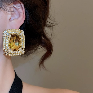 Close-up of vintage gold earrings with amber gemstones and crystals worn by a model