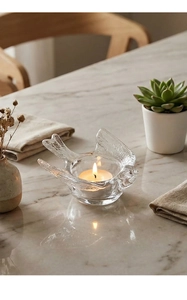 Detailed view of bird-shaped glass candle holder on marble with warm tea light glow