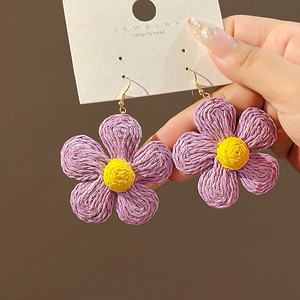 Handwoven raffia flower earrings in purple and yellow on a jewelry display card