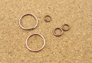 Macro shot of assorted size bronze jump rings for DIY jewelry making on cork base