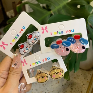 Close-up of three pairs of cute acrylic cartoon earrings in blue, pink and yellow colors