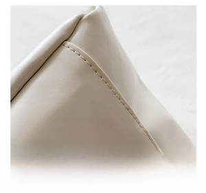 Macro view of precise stitching and premium cream faux leather texture on the bag