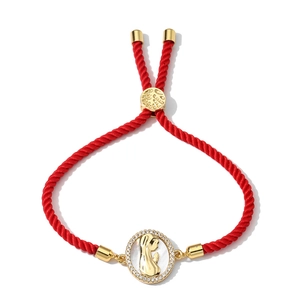 Detail of red braided string bracelet with gold Virgin Mary pendant and zircons