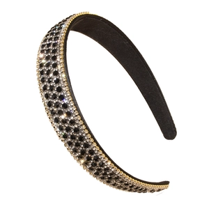 Elegant wide headband featuring sparkling black and clear rhinestones with gold trim edge