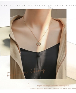 Detail view of a gold vintage embossed star pendant necklace worn by a female model