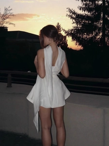 Sexy backless white halter mini dress with a flared skirt shown in an outdoor sunset scene