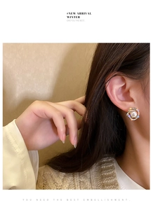 Detail of elegant gold double-circle pearl earrings with shimmering pavé rhinestones