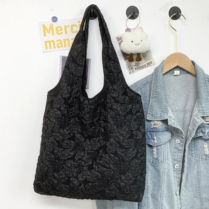Detail of black tote bag with embossed floral texture and wide shoulder strap