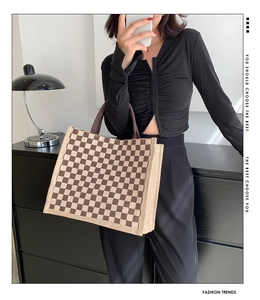 Detail of checkered tote bag made of woven fabric with brown and beige patterns