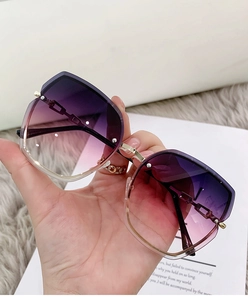 Detail of rimless oversized sunglasses with purple gradient lenses and chain trim
