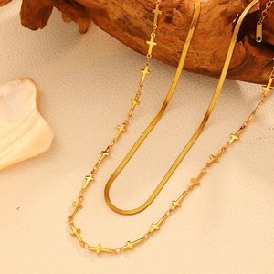 Gros plan du collier double rang doré avec chaîne serpent et pendentifs croix sur bois